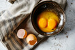 © Helen Rushbrook/Stocksy - Egg yolks in a bowl with egg shells.