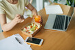 © Marc Tran/Stocksy - smiling woman in office who eats while working