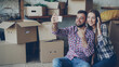 © silverkblack - Happy young couple is making video call with smartphone after relocation. They are greeting friends, showing new house keys and many boxes, chatting and smiling.