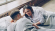 © silverkblack - Young mixed-race couple is lying in bed together and talking, pretty asian woman is speaking to her husband and laughing. Romantic relationship and family concept.