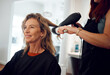 © K Abrahams/peopleimages.com - Hair care, hairdresser and senior woman client hair treatment, professional salon service and hairdryer. Small business, elderly female and brush modern hairstyle, happy customer and beautician lady.