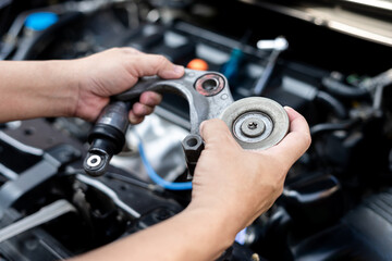 Wall Mural - Close up hand service technician holding engine belt tension of car part to check the damage of roller and hydraulic adjust shock, car service concept in garage with engine room in background