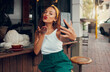 © K Abrahams/peopleimages.com - Cafe, smartphone selfie and black woman with coffee for social media restaurant review, marketing and gen z lifestyle. Influencer customer at coffee shop using phone photography for online profile