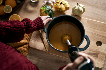 From above of caucasian woman preparing pumpkin soup at home