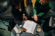 © Maskot - High angle view of young businesswoman signing contract while sitting by female colleague in hotel lounge