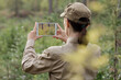 © junky_jess - Woman biologist in uniform take a photo using a digital tablet in a national park in summer, back view, selective focus.