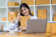 © Wasan - Startup SME small business entrepreneur of freelance Asian woman using laptop and box to receive and review orders online to prepare to pack sell to customers, online sme business ideas.