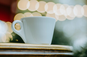 Wall Mural - Moody close up of coffee cup on outdoor terrace table with bokeh Christmas lights background