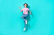 Full length photo of ecstatic cute girlish woman wear pink t-shirt denim jeans flying jumping champion isolated on teal color background