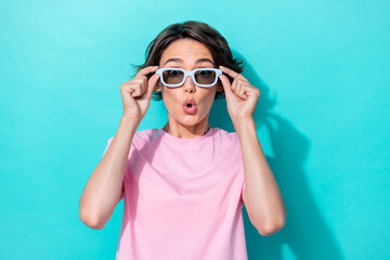 Poster - Photo of excited speechless staring girl with bob hairdo pink t-shirt hands hold sunglass impressed news isolated on teal color background