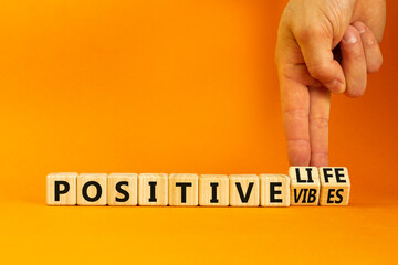Wall Mural - Positive vibes and life symbol. Concept words Positive vibes or Positive life on wooden cubes. Businessman hand. Beautiful orange background. Business positive vibes life concept. Copy space