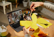 © master1305 - Young man sitting at home, holds a master class on origami using video call, conference with friends, students. Hobbies and leisure activities. Remote training, online classes