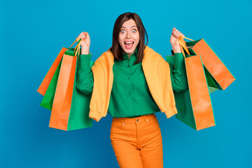 Poster - Portrait of astonished positive lady open mouth cant believe hold packages isolated on blue color background