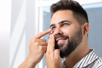 Poster - Young man putting in contact lens indoors