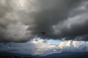 Wall Mural - Modern white airplane flying in sky with clouds, low angle view