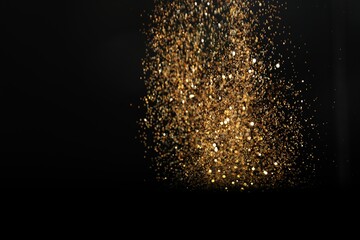 Wall Mural - shiny golden glitter falling down on black background. bokeh effect