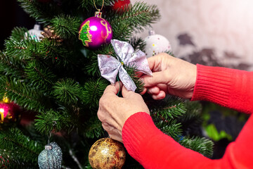 Wall Mural - A woman decorates a Christmas tree, the atmosphere of the holiday