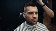 © LIGHTFIELD STUDIOS - Barber standing behind client in hairdressing cape in barbershop.