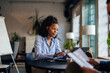 © bnenin - Focused African businesswoman typing over the laptop, working at the co-working place.