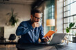 © bnenin - Concentrated businessman drinking a cup of coffee and reading a workbook.