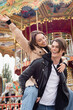 © LIGHTFIELD STUDIOS - stylish man in black jacket piggybacking happy girlfriend in amusement park.