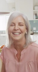 Wall Mural - Vertical video portrait of happy senior caucasian woman smiling to camera in kitchen