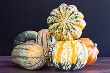 Two Stacked Carnival Squash Surrounded By Delicata Squash, Gold Acorn Squash, And Kabocha Squash.