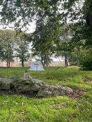 Poster - Vertical shot of a squirrel on a rock in a park with a grave in the background and greenery around