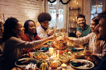 Wall Mural - Happy friends toasting with wine during Thanksgiving dinner at dining table.