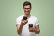 © Damir Khabirov - Guy laughing at message holding cellphone and drinking coffee, isolated on green