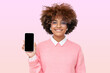 African girl in glasses holding smartphone with blank screen with copy space, showing it to viewer