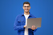 © Damir Khabirov - Studio portrait of young man standing holding laptop and looking at camera with happy smile