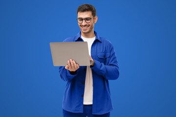 Young man holding laptop surfing, browsing online, typing message or watching movie