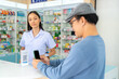 © CandyRetriever  - Medical pharmacy and contactless payment concept. Asian man patient customer using mobile phone scan QR code on counter making online banking payment buying medicine, drugs and supplement in drugstore