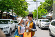© CandyRetriever  - Young Asian couple enjoy and fun outdoor lifestyle shopping together at street market on summer holiday vacation. Man and woman couple eating street food while walking and shopping at weekend market.