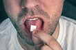 Man with LSD on the tongue On a black background. white stamp with narcotic acid on the tongue.