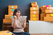 © sutthinon602 - Startup small business SME, Entrepreneur owner using smartphone or tablet taking receive and checking online purchase shopping order to preparing pack product box. Selling online ideas concept