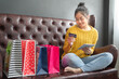 © sutthinon602 - Young woman on sofa shopping online with laptop, Young woman holding credit card and using laptop computer. Online shopping concept. Film tone