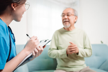 Asian caregiver talking senior male patient checkup in living room at home. Older elderly man consults after physical therapy. Nurse assistance rescue concept.