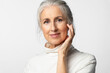 © deniskomarov - Elderly woman, age model, smoothes out wrinkles, looking good and smiling and looking at the camera on white background