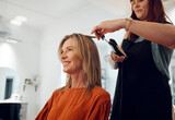 Salon, haircut and style with a woman customer straightening her hair for beauty or wellness. Fashion, client and hair with a female hairdresser or beautician at work with a consumer for haircare