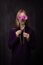 Fine Art Studio Portrait Of Woman In Purple Dress Holding Pink Gerbera Flowers As Eyes