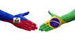 Handshake between Brazil and Haiti flags painted on hands, isolated transparent image.