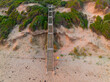 © Austockphoto - Aerial view of a long staircase climbing from a beach up over sand dunes
