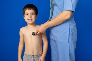 The doctor listens to the heart and lungs of a 5-year-old boy with a stethoscope.