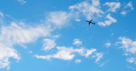 Wall Mural - The passenger airplane is flying far away in the blue sky and white clouds. Aircraft in the air. International passenger air transportation. Horizontal stories