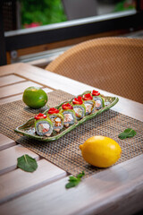 Canvas Print - Sushi rolls with cheese sauce, strawberries and salmon on a wooden table on the restaurant's summer terrace