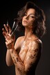Alluring naked woman with creative body art and brushes in hands in studio