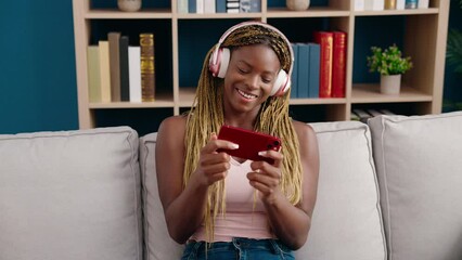 Wall Mural - African american woman watching video on smartphone sitting on sofa at home