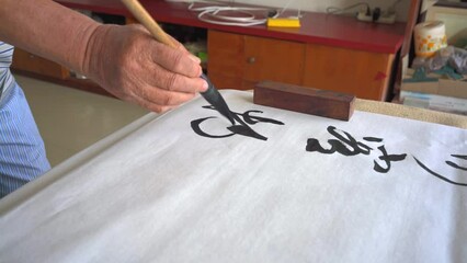 Wall Mural - an old calligrapher is writing calligraphy characters, creating calligraphy works.